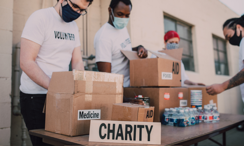 people putting items in box labeled 'charity'